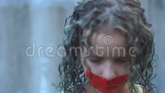特写一个卷曲悲伤的少年女孩的肖像她的嘴用红色胶带粘在上面侵犯言论自由视频的预览图