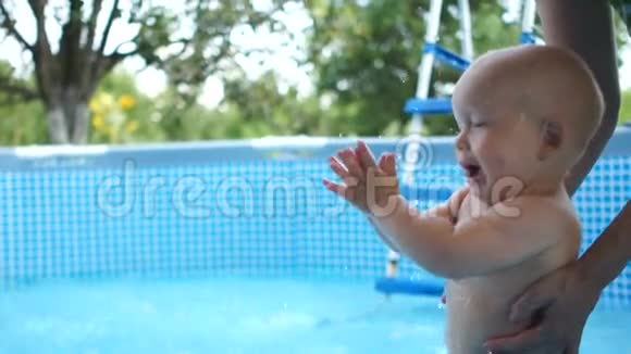 快乐的一岁宝宝在泳池里夏天拍手吹泡泡快乐的童年视频的预览图