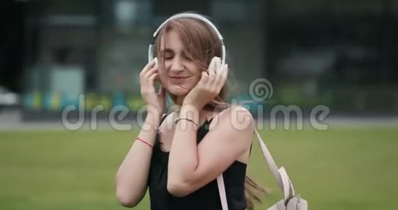 年轻迷人的城市背景女孩带着耳机听音乐视频的预览图