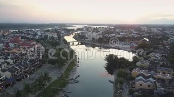鸟瞰宁静的河流在日落时分蜿蜒在小镇上视频的预览图