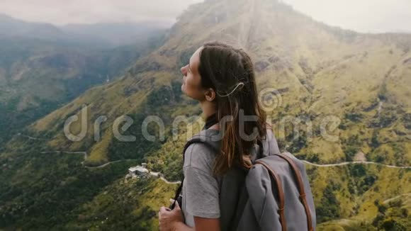 镜头围绕年轻平静的旅游妇女与背包享受风在史诗山景斯里兰卡的头发视频的预览图