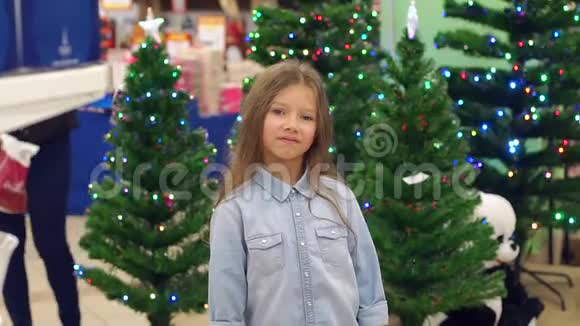 一个在超市里以圣诞树为背景的有趣的小女孩视频的预览图