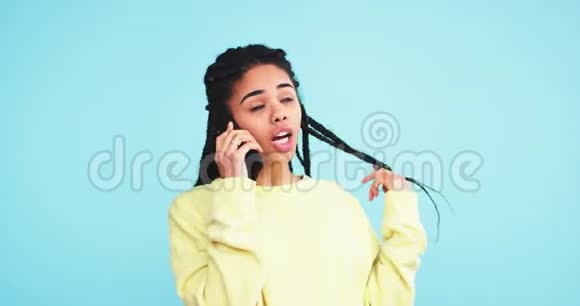 非常有魅力的漂亮年轻女性非洲裔在一个蓝底墙的工作室里用手机说话视频的预览图