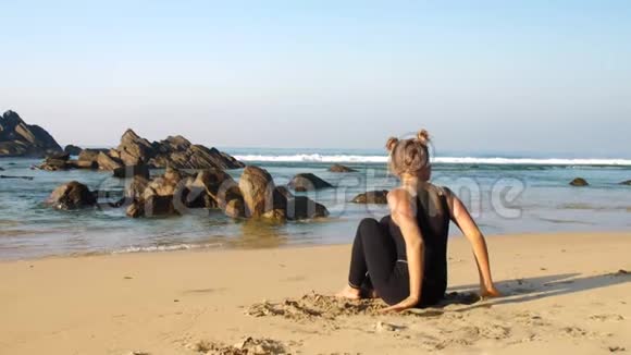 女士在沙滩上练习瑜伽以对抗褐色岩石视频的预览图