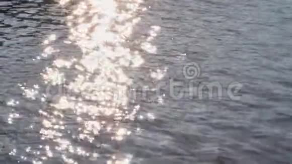 平静的蓝色波浪在海洋或河流中金色耀眼的阳光和水面上的涟漪摘要bokeh背景视频的预览图