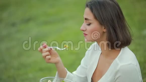 坐在草地上吃沙拉的美女视频的预览图