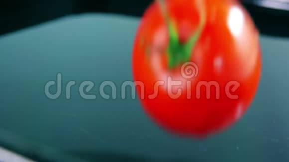 慢镜头红色成熟的西红柿飞溅在水上翻滚视频的预览图