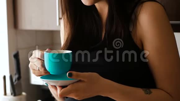 美丽的女孩早上在厨房喝蓝色杯子里的咖啡中型射击视频的预览图