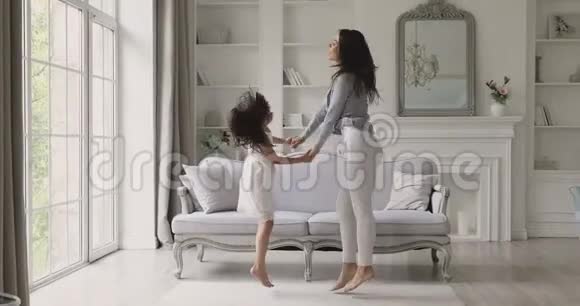 有趣的活跃的无忧无虑的妈妈和孩子的女儿跳在一起跳舞视频的预览图