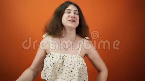 穿格子衬衫的女人站在橙色背景上打哈欠视频的预览图