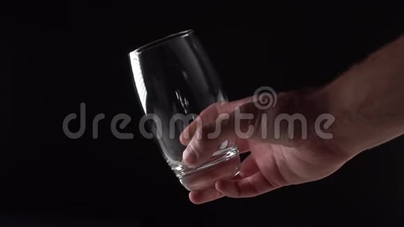 水从上面涌出在黑色的背景上用手盛一个杯子视频的预览图