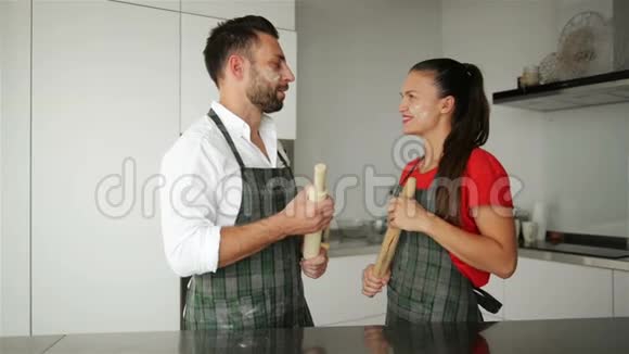 穿着围裙的微笑情侣的肖像住在轻盈现代宽敞的厨房里他们玩得很开心视频的预览图