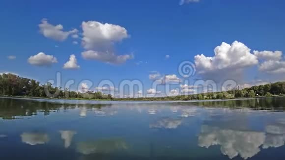 在阳光明媚的夏日蓝天上的云彩在湖面上流逝视频的预览图