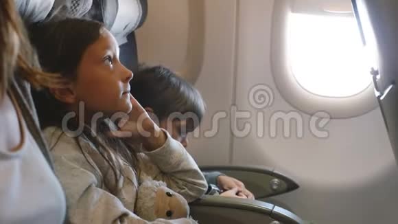 两个小无聊的孩子在长时间的飞机飞行中环顾四周和家人一起去度假视频的预览图