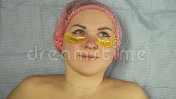 一位戴手套的男性美容师将胶原蛋白垫放在女人下眼皮上视频的预览图
