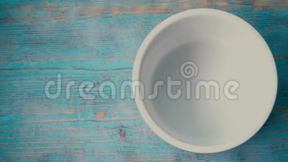坠落的玉米片和蓝色木桌上的碗超级慢动作视频的预览图