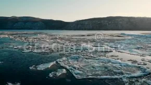 空中观景冰冻河流的足迹在给定的裸露的群山中覆盖着雪冬天寒冷的景色视频的预览图