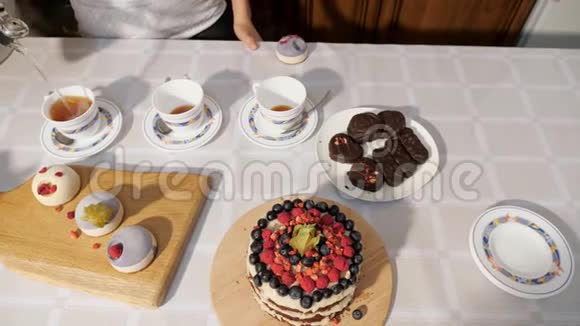 女人手在家里的杯子里倒茶在桌子上放糖果来庆祝生日视频的预览图