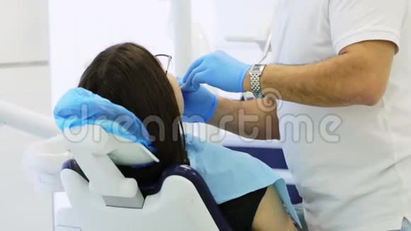 口腔医生对坐在牙科椅上的妇女进行预防性检查视频的预览图