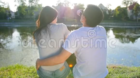 浪漫的夫妇喝咖啡坐在池塘附近的绿草上后景夫妻信任爱情和幸福视频的预览图