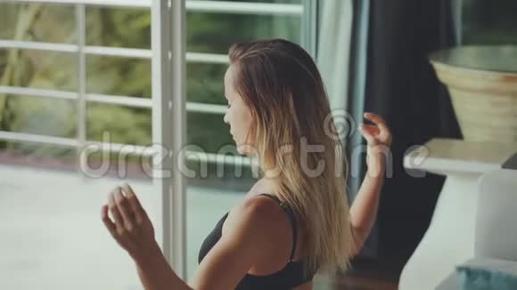 做瑜伽的时间到了有魅力的年轻女性在家休息时锻炼身体坐在瑜伽莲花的位置视频的预览图