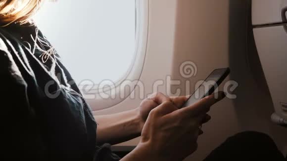 特写背景镜头年轻女性手使用智能手机移动办公商务应用程序在飞机窗口座位视频的预览图