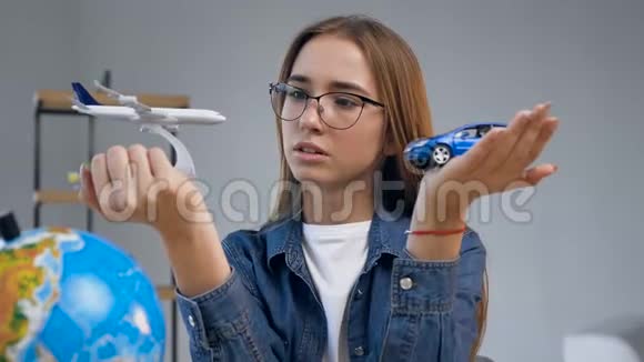 困惑的年轻女人手里拿着玩具飞机和汽车视频的预览图