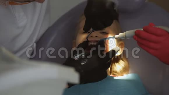 三岁的小女孩坐在牙科办公室的椅子上牙医对牙齿进行例行清洁视频的预览图