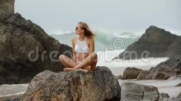 性感的女人坐在大西洋的岩石上视频的预览图