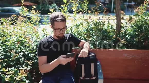 有智能手机的人坐在长凳上视频的预览图
