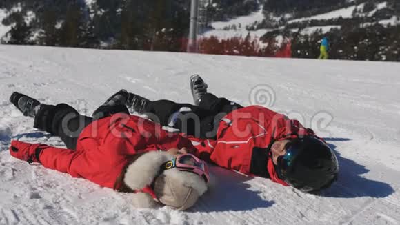 快乐的一对滑雪者躺在雪地里年轻人在山区度过许多有趣的寒假视频的预览图