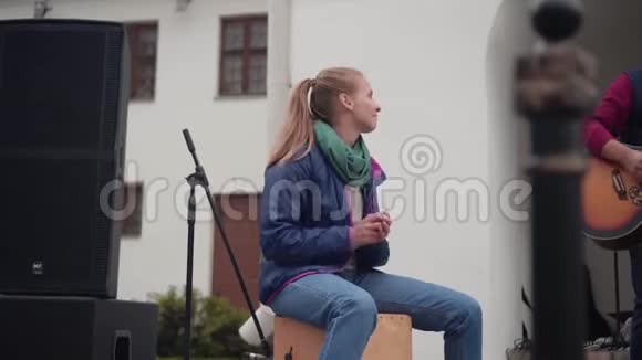 女孩街头音乐家坐在低音炮上跺脚拍手女打击乐手视频的预览图