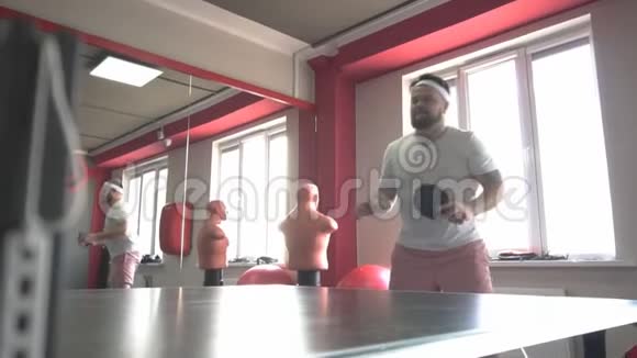 肥胖的白种人留着胡子在现代的健身房打乒乓球体重超标动作迟缓视频的预览图
