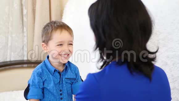 一个快乐的孩子脸上带着微笑抱着他的妈妈躺在白色的沙发上视频的预览图