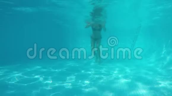 穿着比基尼的白人女孩在蓝色游泳池的镜头下游泳从水下观看视频的预览图