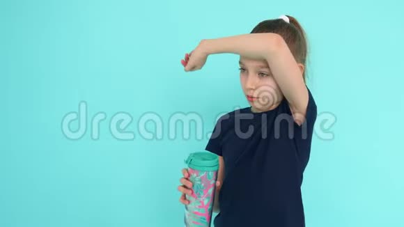 年轻女孩在绿色背景下健身房时从健身瓶中喝水视频的预览图