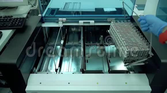 女人把装有试管的架子放在机器上实验室的电子设备机械设备视频的预览图