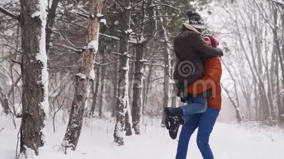 男人旋转或旋转快乐的女朋友牵着她在松林下的雪有爱的夫妻玩得开心视频的预览图