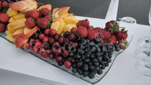 新鲜蓝莓草莓樱桃切片苹果芒果和菠萝在一个长的长方形盘子里视频的预览图