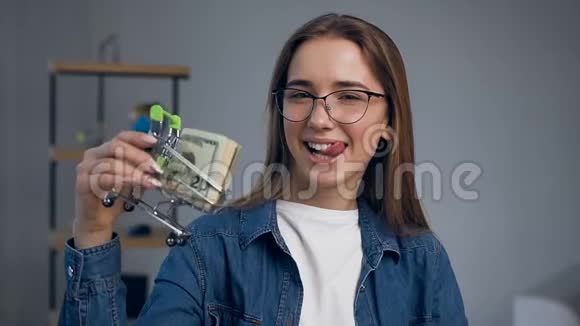 肖像画的幸福年轻女子玩钱在购物车的手中视频的预览图