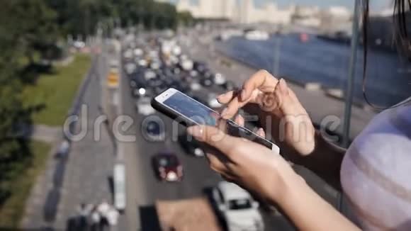 美丽迷人的年轻女子站在桥上使用智能手机下面是一串汽车视频的预览图
