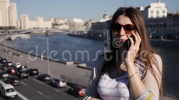 美丽迷人的年轻女子站在桥上使用智能手机下面是一串汽车视频的预览图