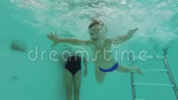 一个小男孩潜入游泳池睁开眼睛在水下游泳看着摄像机视频的预览图