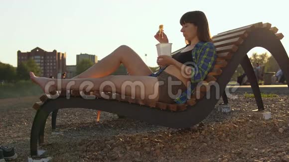 女孩在河岸的鹅卵石海滩上吃热面视频的预览图