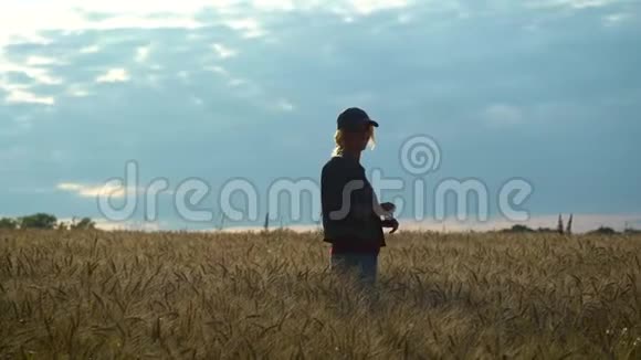 一个苗条的女人走在麦田上在阳光明媚的夏日微笑视频的预览图