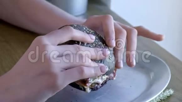 一个可爱的年轻女孩在咖啡馆里有一个巨大的汉堡他张开嘴咬掉一块汉堡街头食品视频的预览图