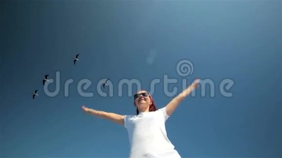 年轻的女孩子在飞翔的海鸥的天空中放松视频的预览图