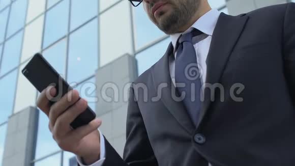 在户外使用移动商务应用程序在智能手机上打字时穿西装的忙碌男子视频的预览图