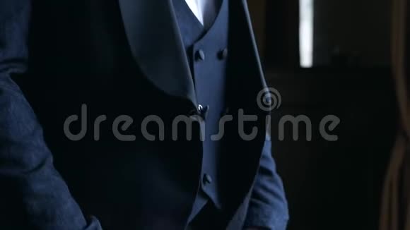 男人在一件经典的蓝色夹克上扣上一个纽扣穿着蓝色礼服的优雅男人视频的预览图