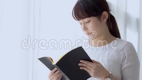 美丽的肖像年轻的亚洲妇女放松站立学习与阅读书考试在卧室在家里视频的预览图